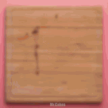 a wooden bowl filled with chopped nuts on a pink background