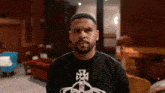 a man with a beard wearing a black shirt with a cross on it