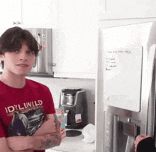 a man wearing a red shirt that says idyllwild stands in a kitchen