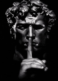a black and white photo of a statue making a silence sign