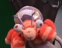a person is holding a stuffed animal that looks like a crab with big eyes .