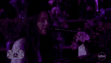 a woman is singing into a microphone in front of a mercedes logo .