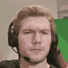 a man wearing headphones and a microphone makes a funny face .