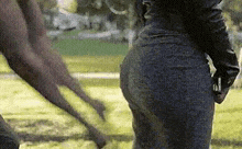 a woman is standing next to a kangaroo in a park and looking at it .