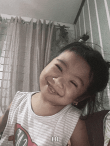 a little girl wearing a shirt that says hi is smiling
