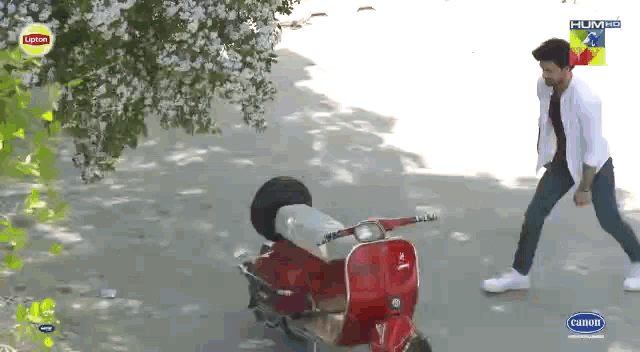 a man standing next to a red scooter that says lipton on the front