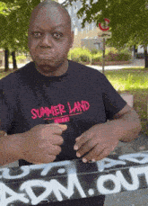 a man wearing a summer land shirt is holding a sign
