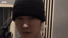 a close up of a person wearing a beanie in front of a microphone .