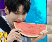 a young man is eating a slice of watermelon with his mouth open .