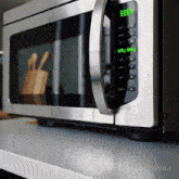 a stainless steel microwave with a green display that reads eeby