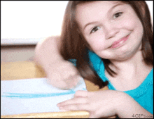 a girl in a blue shirt is smiling and making a funny face