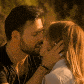 a man and a woman are kissing and the woman is touching the man 's face