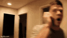 a man is talking on a cell phone in a room .