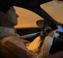 a man in a suit is driving a car and looking at his phone