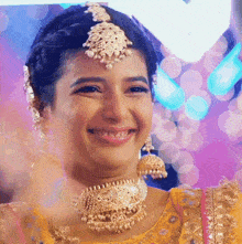 a woman wearing a yellow top and gold jewelry smiles