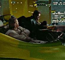 two men are sitting in a yellow and green vehicle with the letters tc on it