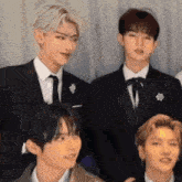 a group of young men wearing suits and ties are standing next to each other .