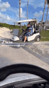 a man is driving a golf cart on a road with a tiktok watermark