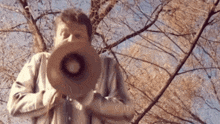 a man in a striped shirt is holding a megaphone in front of a tree