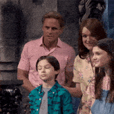 a family posing for a picture with a boy wearing a shirt with sharks on it