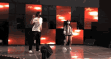a man and a woman are dancing on a stage in front of a red background