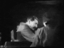 a black and white photo of a man standing next to a woman in a dark room .