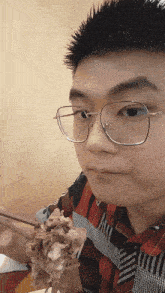 a young man wearing glasses is holding a piece of meat in his hand