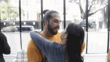 a man and a woman are hugging and kissing in front of a window