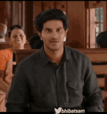 a man in a black shirt smiles in front of a twitter icon