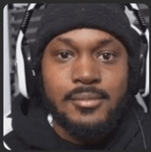 a man with a beard wearing a black hat and headphones