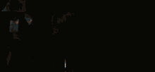 a man in a hood is standing in a dark room holding a gun .