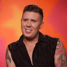a man with a tattoo on his arm is smiling and wearing a black shirt