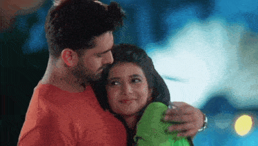 a man and a woman are hugging each other and looking at the camera .