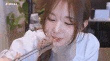 a young woman is eating food with chopsticks and smiling .