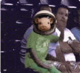 a pig wearing a helmet is sitting in front of a group of people