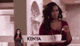 a woman is holding a cup of coffee in front of a kenya sign