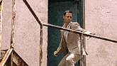 a man in a suit and sunglasses is standing on a railing .