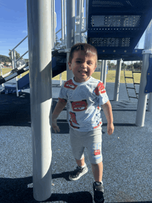 a young boy wearing a lightning mcqueen shirt is standing in front of a playground