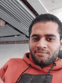 a man with a beard wears a red hoodie with a black galaxy print