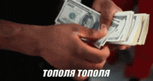 a person is holding a stack of 100 dollar bills in their hand