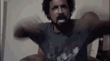 a man with a beard is sitting on a bed with his arms outstretched and screaming .