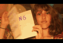 a woman is holding a piece of paper that says ng on it