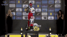 a man stands on a podium holding a trophy in front of a wall that says prodomus