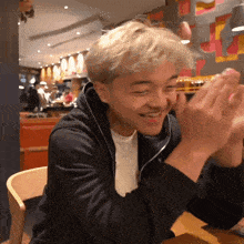 a man in a black jacket is clapping his hands
