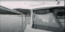 a white boat is floating on a body of water with mountains in the background