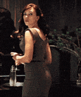 a woman in a dress is standing in front of a vase