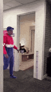 a man in a red white and blue hoodie is walking through a doorway that says vignale on the wall