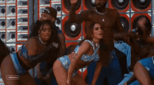 a group of people are dancing in front of a wall of speakers