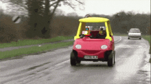 a red toy car with a yellow top has a license plate that says xklw hbl