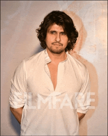 a man in a white shirt is standing in front of a filmfare poster